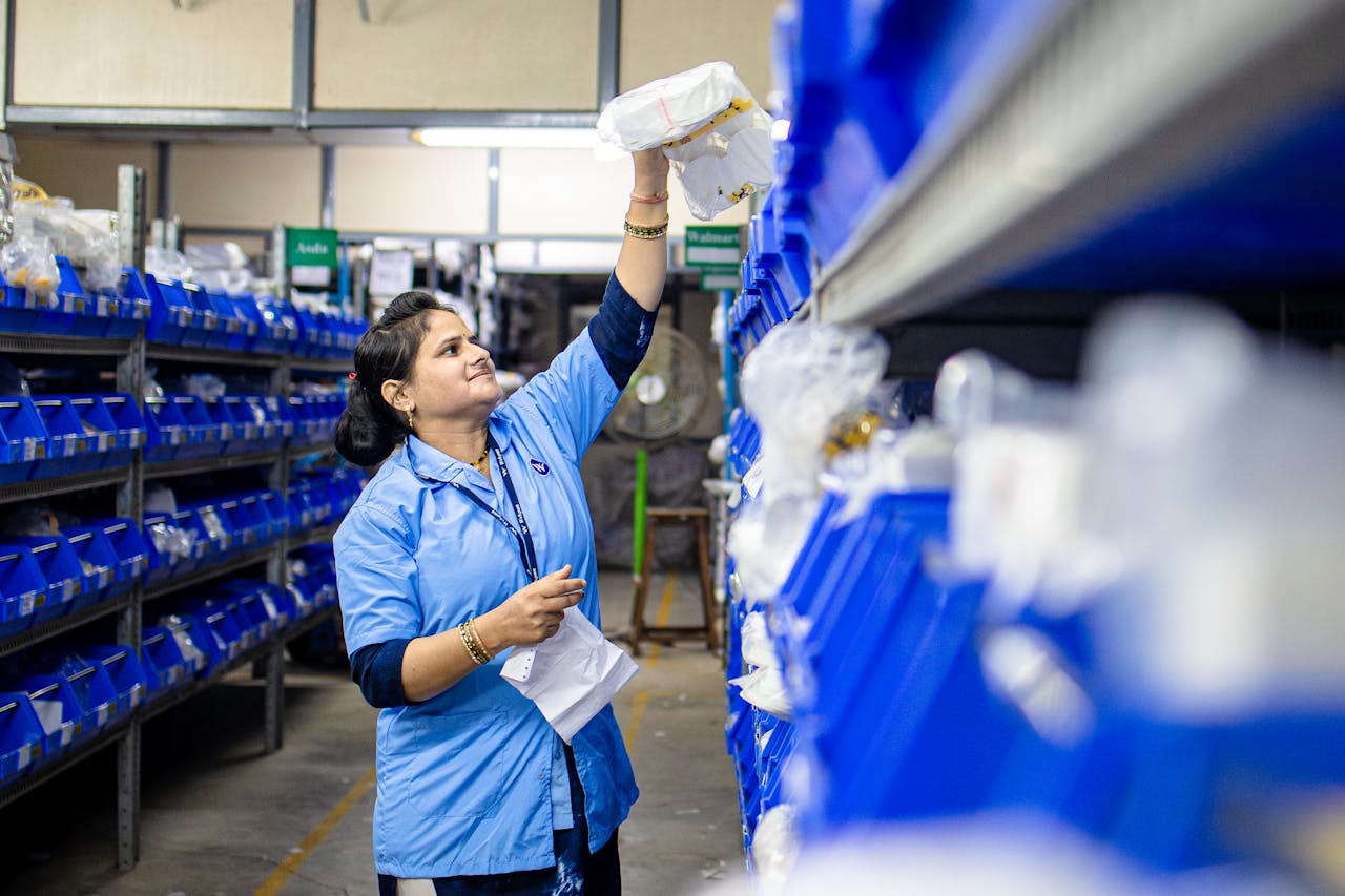 services-bg Female warehouse worker organizing inventory on blue industrial shelves. Efficient logistics management.