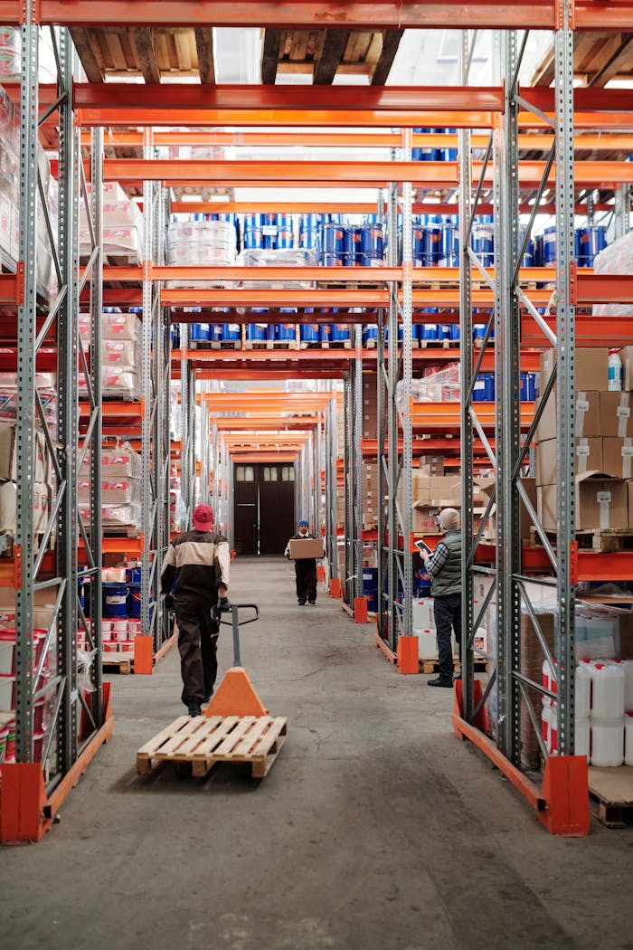 home-hero Workers arrange inventory on shelves in a large industrial warehouse.
